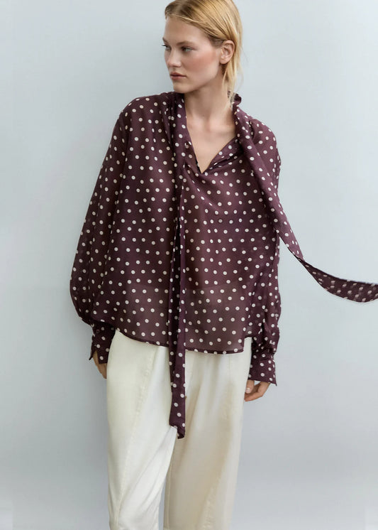 Woman wearing a polka dot blouse with a plain background