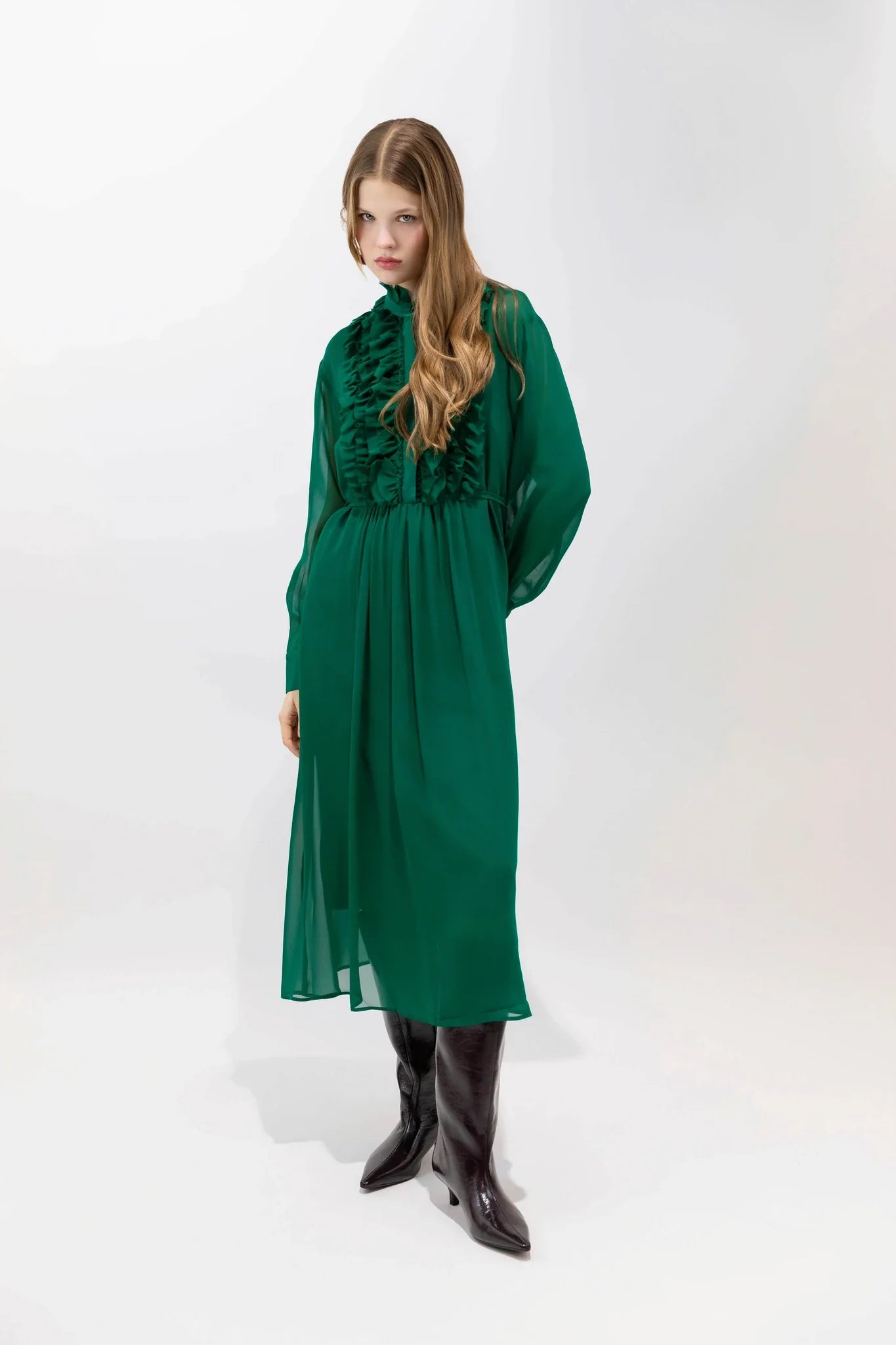 Woman wearing a green dress with ruffled details on a white background