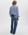 Person wearing a blue and white striped shirt and blue jeans on a white background