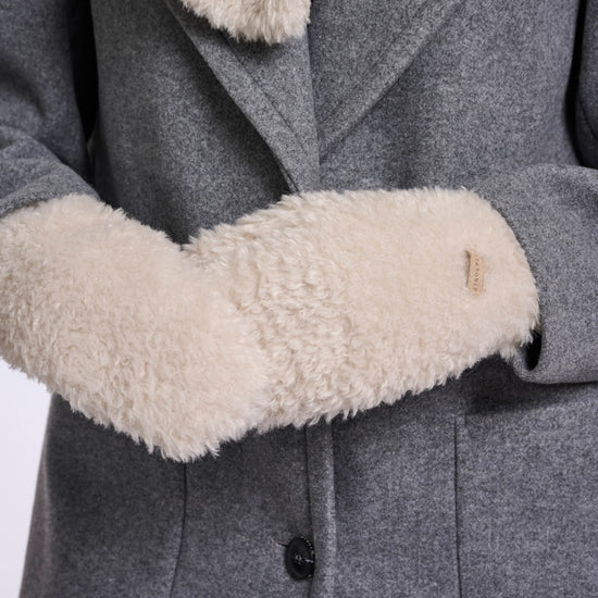 Close-up of a gray wool coat with a thick cream-colored shearling lining on the collar and cuffs, featuring a single black button closure.