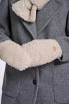 Close-up of a gray wool coat with a thick cream-colored shearling lining on the collar and cuffs, featuring a single black button closure.