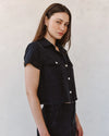 woman wearing black denim short sleeve shirt with white background side view