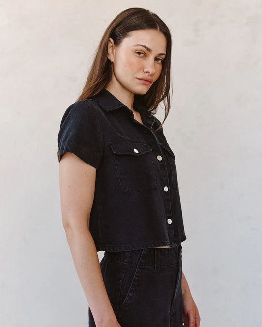 woman wearing black denim short sleeve shirt with white background side view