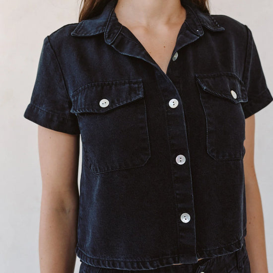 woman wearing black denim short sleeve shirt with white background - close up 