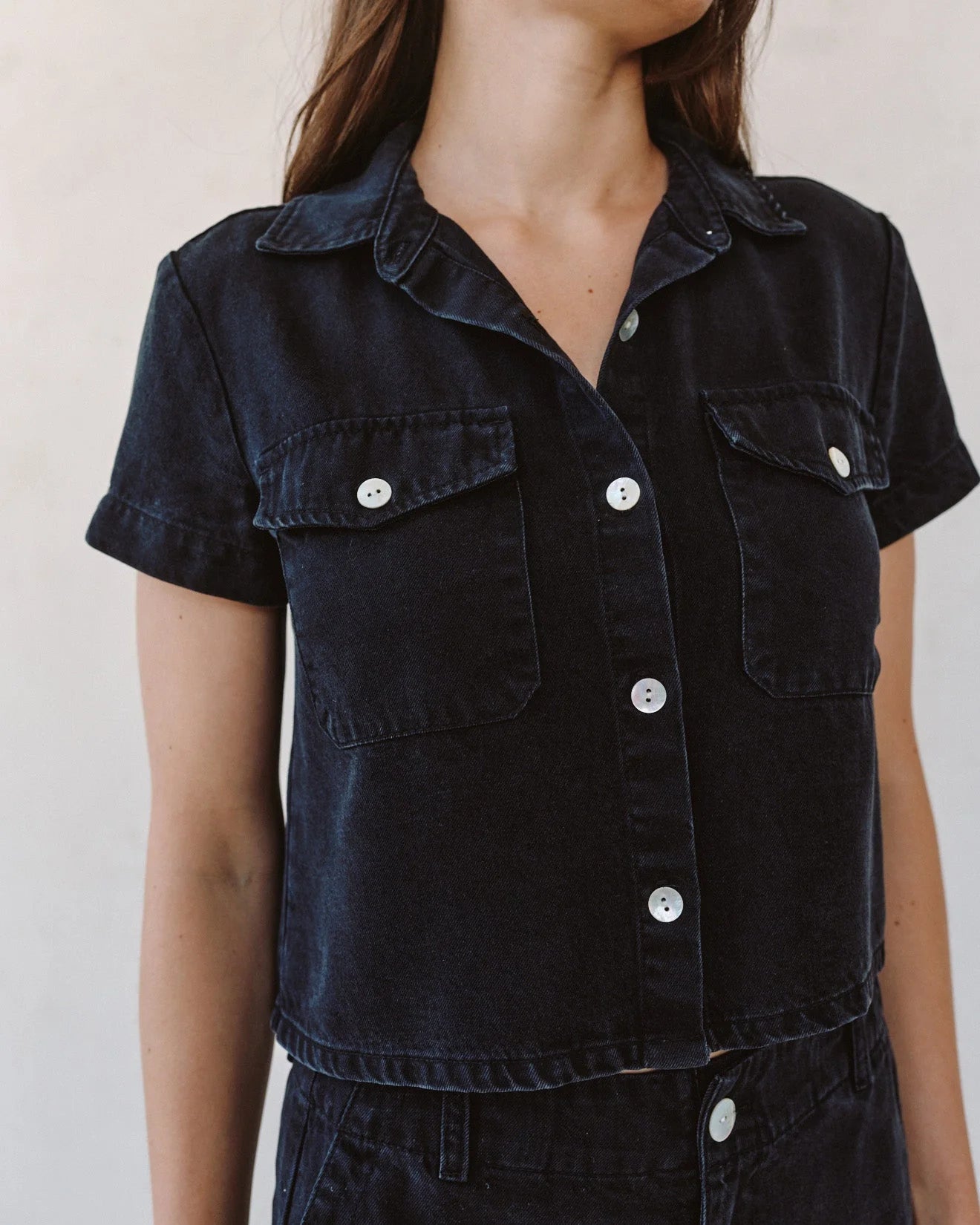 woman wearing black denim short sleeve shirt with white background - close up 