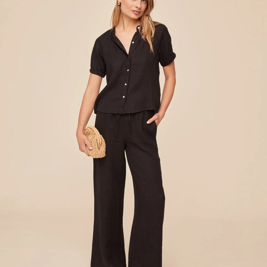 Black short sleeve shirt paired with black wide leg trousers
