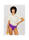 Woman wearing a white t-shirt with text and purple high-waisted bikini bottoms, holding a yellow object.