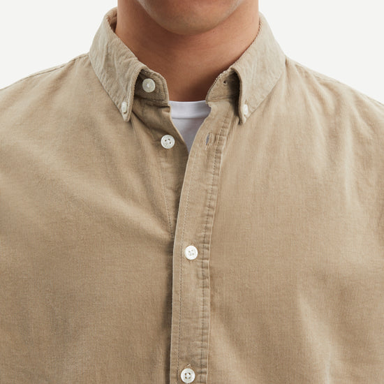 light brown baby cord button down shirt with single button cuff and curved hem close up