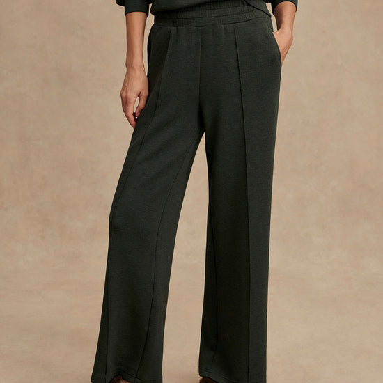 Person wearing dark gray wide-leg pants on a beige background from Varley