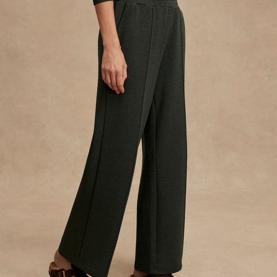 Person wearing dark green wide-leg pants on a beige background from Varely