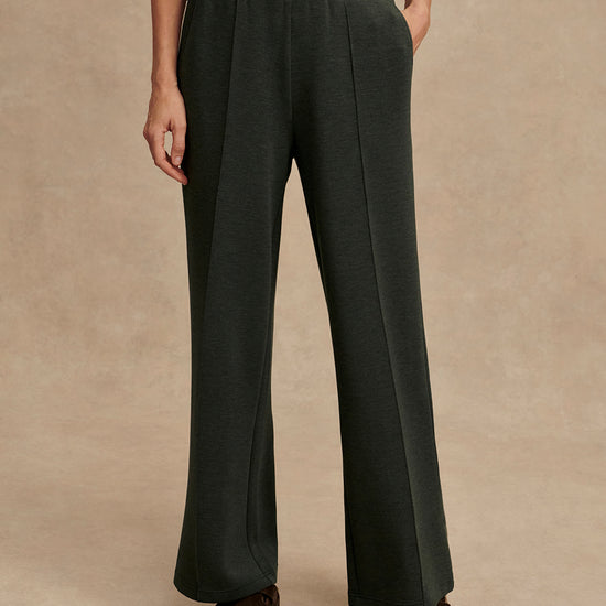 Dark green wide-leg pants worn by a person on a beige background from Varley