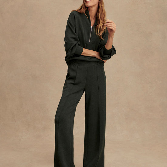 Woman wearing a dark outfit with a cap against a beige background from Varley