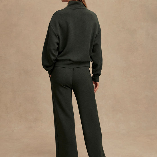 Person wearing a dark green outfit with a brown cap on a beige background from Varley