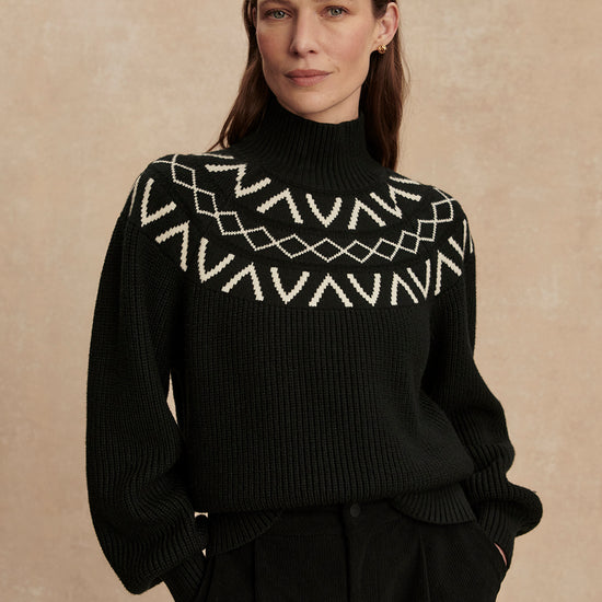 black ribbed jumper with high neck, white varley detailing around the neckline
