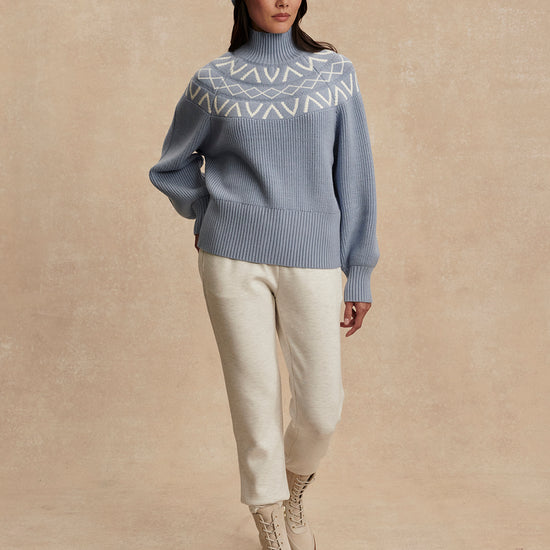 blue ribbed jumper with white varley logo and high neck model shot