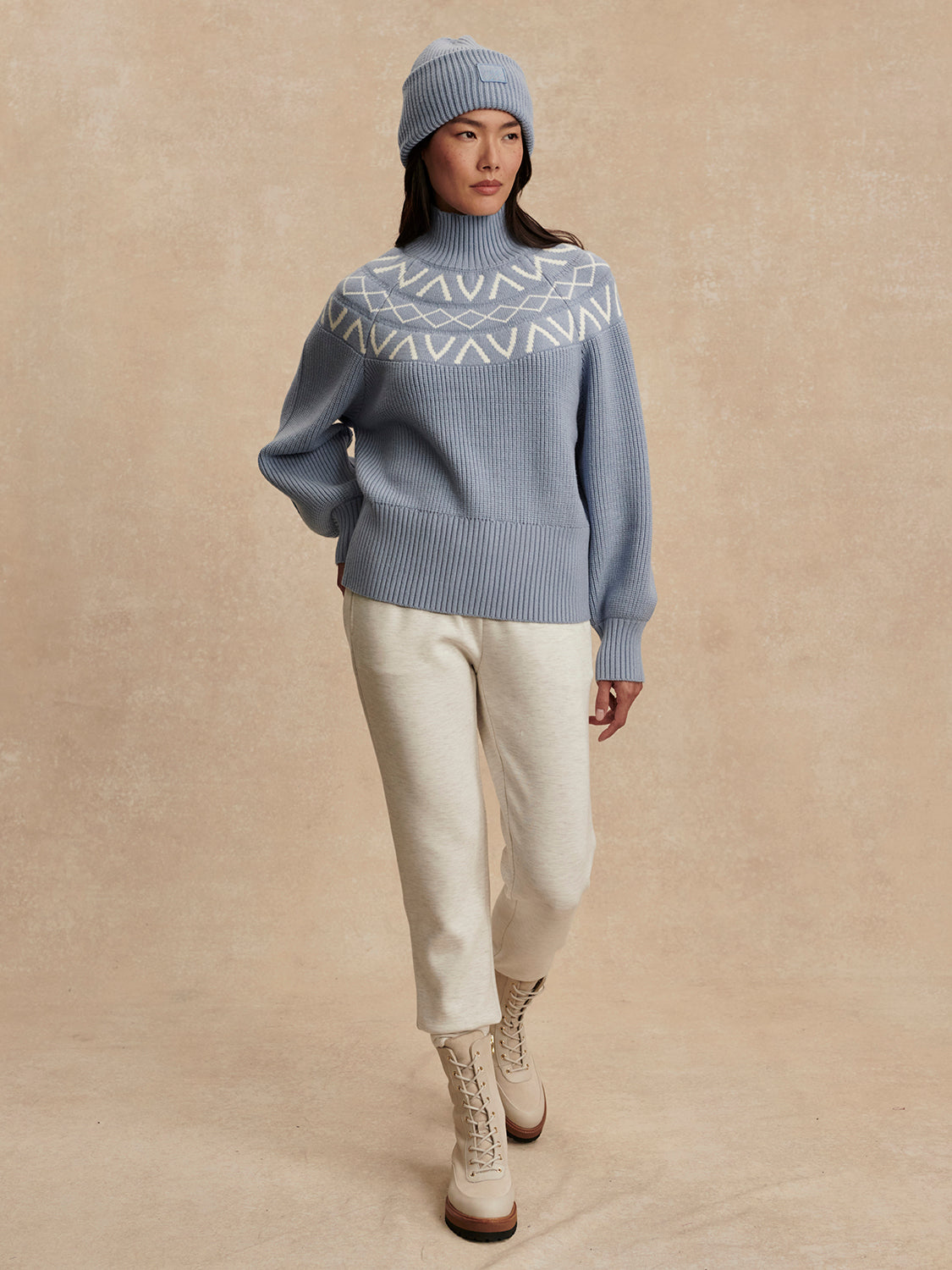blue ribbed jumper with white varley logo and high neck model shot