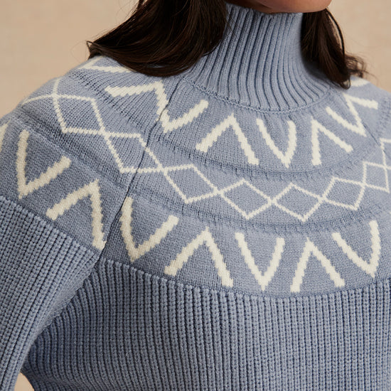 blue ribbed jumper with white varley logo and high neck close up