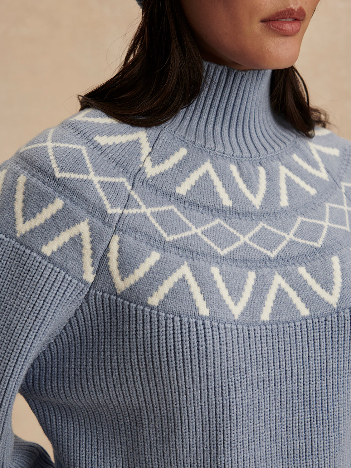 blue ribbed jumper with white varley logo and high neck close up