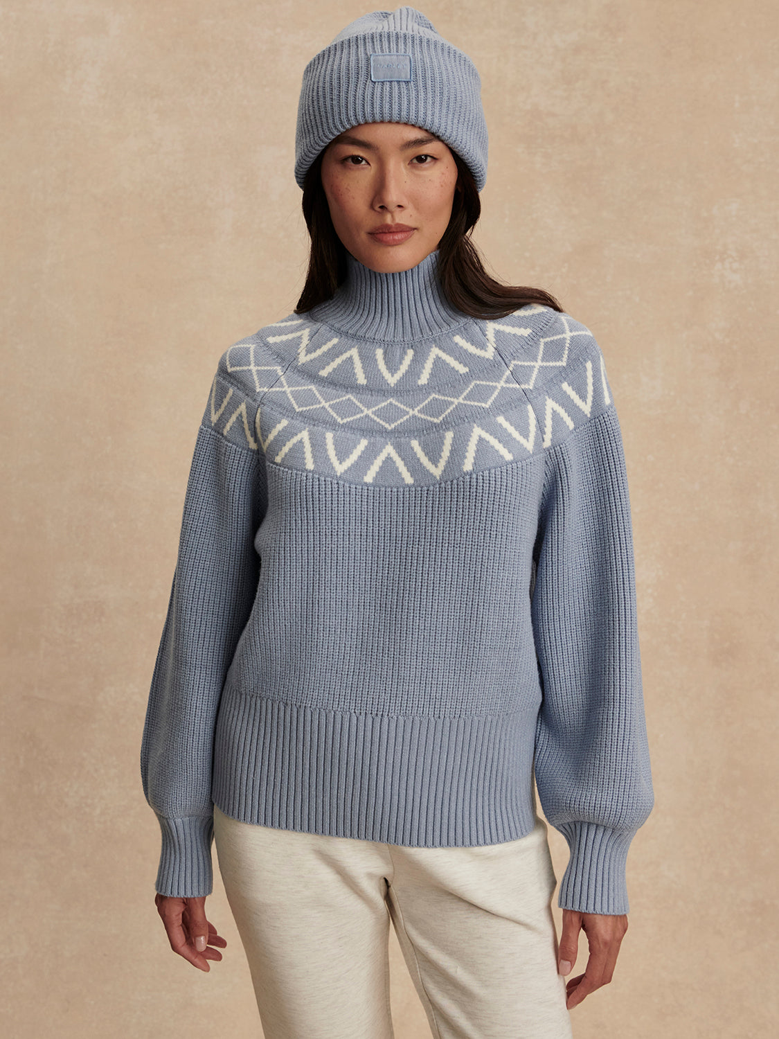 blue ribbed jumper with white varley logo and high neck model shot