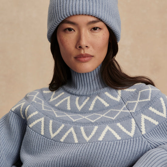 blue ribbed jumper with white varley logo and high neck close up