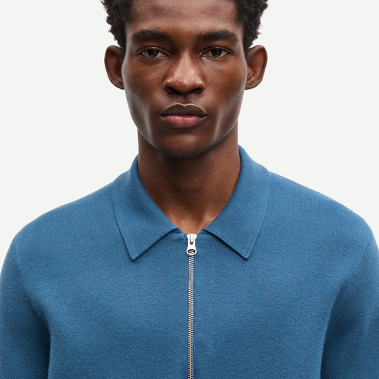 Blue long-sleeve polo shirt with a half zipped placket and relaxed fit close up