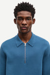 Blue long-sleeve polo shirt with a half zipped placket and relaxed fit close up