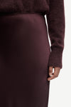 Close-up of a person wearing a burgundy sweater and skirt on a white background
