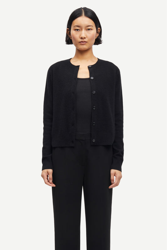 Person wearing a black cashmere cardigan over a black top and pants on a white background from Samsoe Samsoe