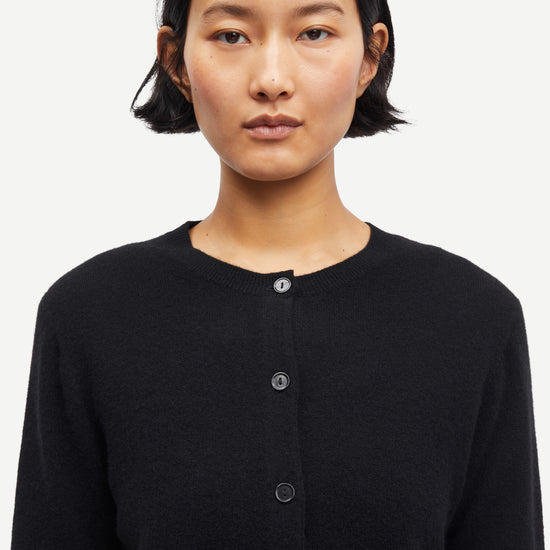 Person wearing a black cardigan on a white background from Samsoe Samsoe
