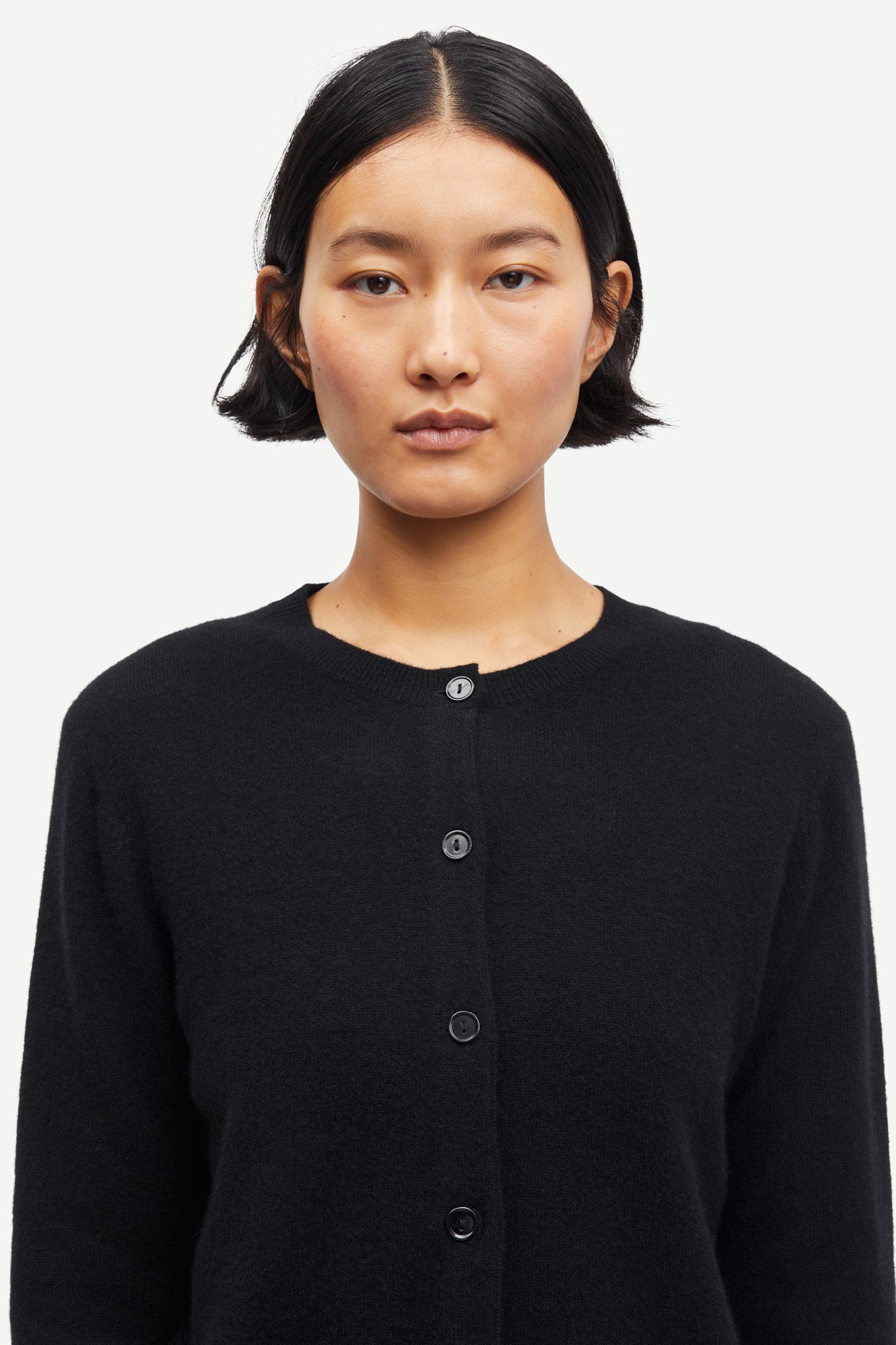 Person wearing a black cardigan on a white background from Samsoe Samsoe
