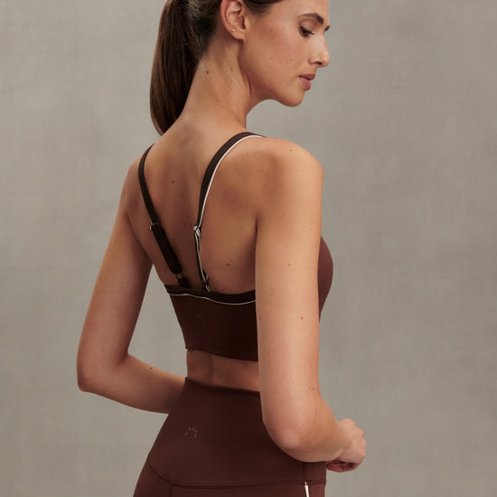 brown sports bra with white piping form varley model rear view