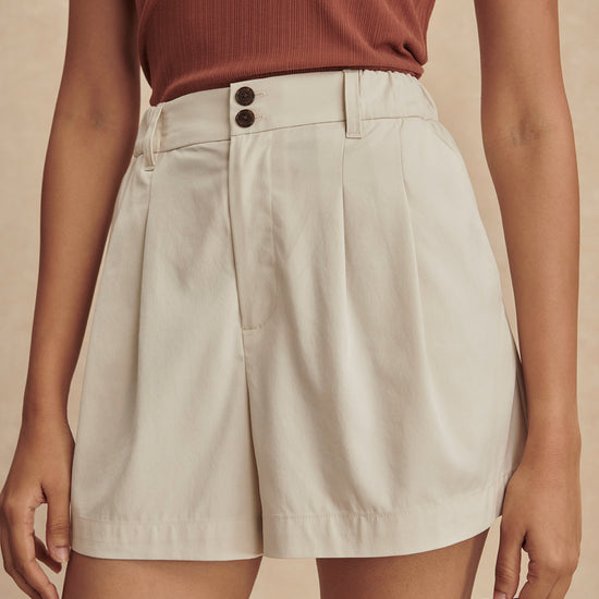 ivory chino style tailored shorts with double buttons and pleat detailing from varley model shot