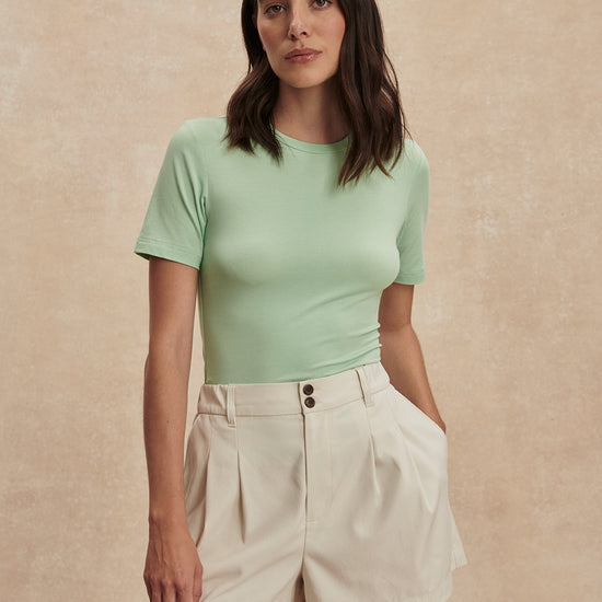 ivory chino style tailored shorts with double buttons and pleat detailing from varley model shot