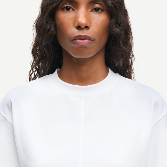 Person wearing a plain white shirt against a light background from Samsoe Samsoe