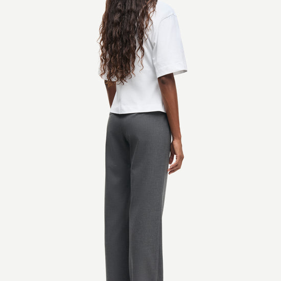 Person wearing a white top and gray pants on a white background rear view from Samsoe Samsoe