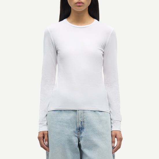 Person wearing a white long-sleeve shirt and light blue jeans on a white background from Samsoe Samsoe