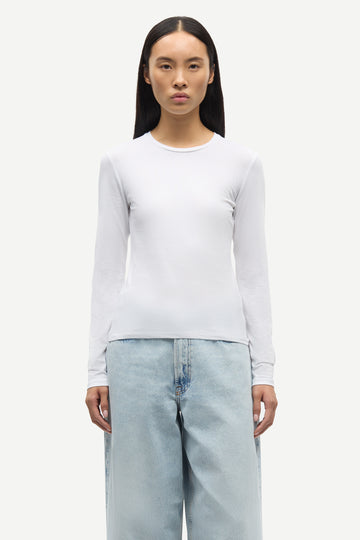 Person wearing a white long-sleeve shirt and light blue jeans on a white background from Samsoe Samsoe