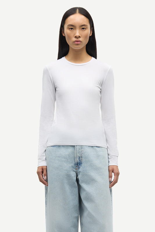 Person wearing a white long-sleeve shirt and light blue jeans on a white background from Samsoe Samsoe