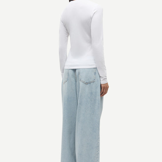 Person wearing a white long-sleeve top and light blue jeans on a white background from Samsoe Samsoe