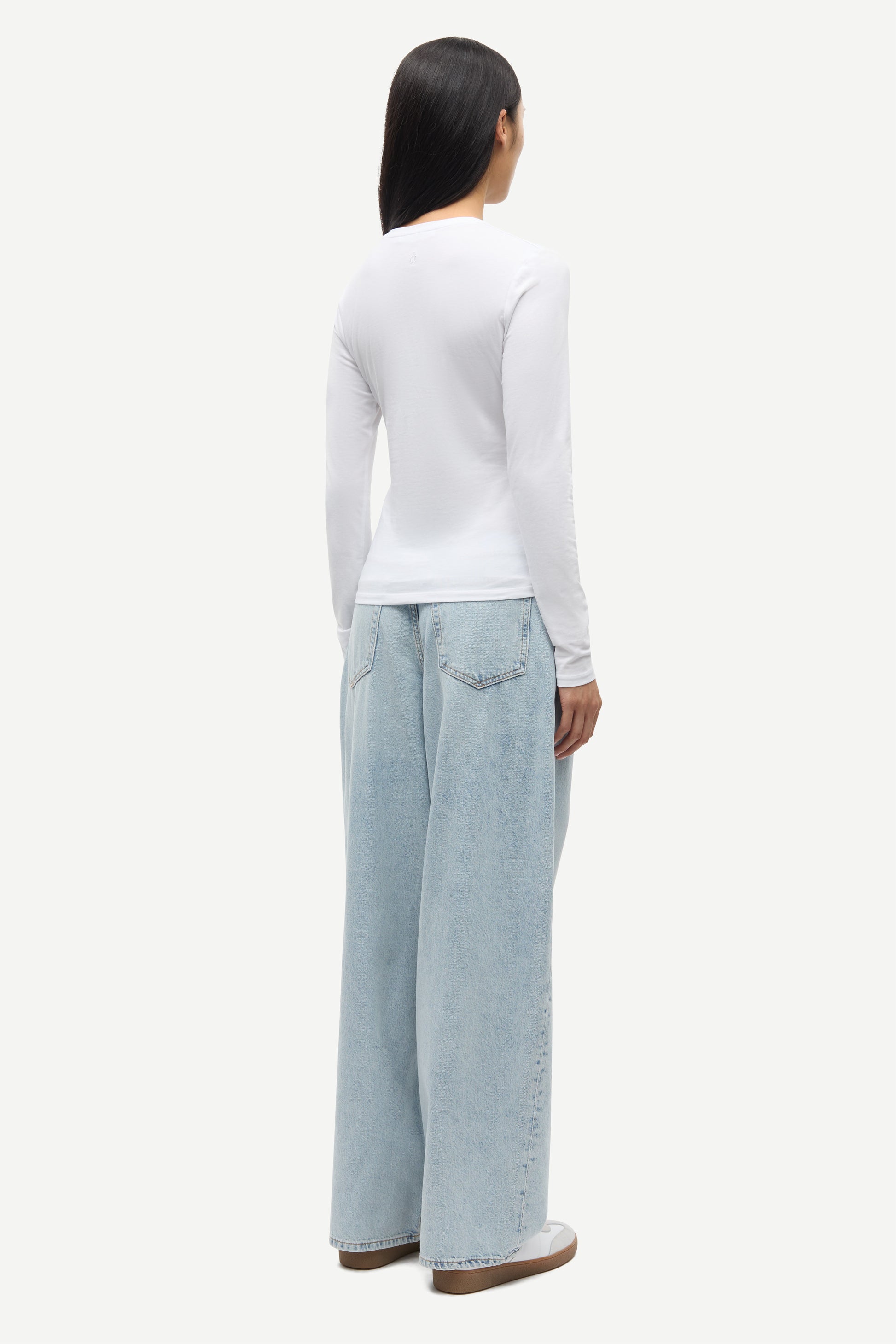 Person wearing a white long-sleeve top and light blue jeans on a white background from Samsoe Samsoe