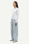 Woman wearing a white long-sleeve top and light blue pants on a white background from Samsoe Samsoe