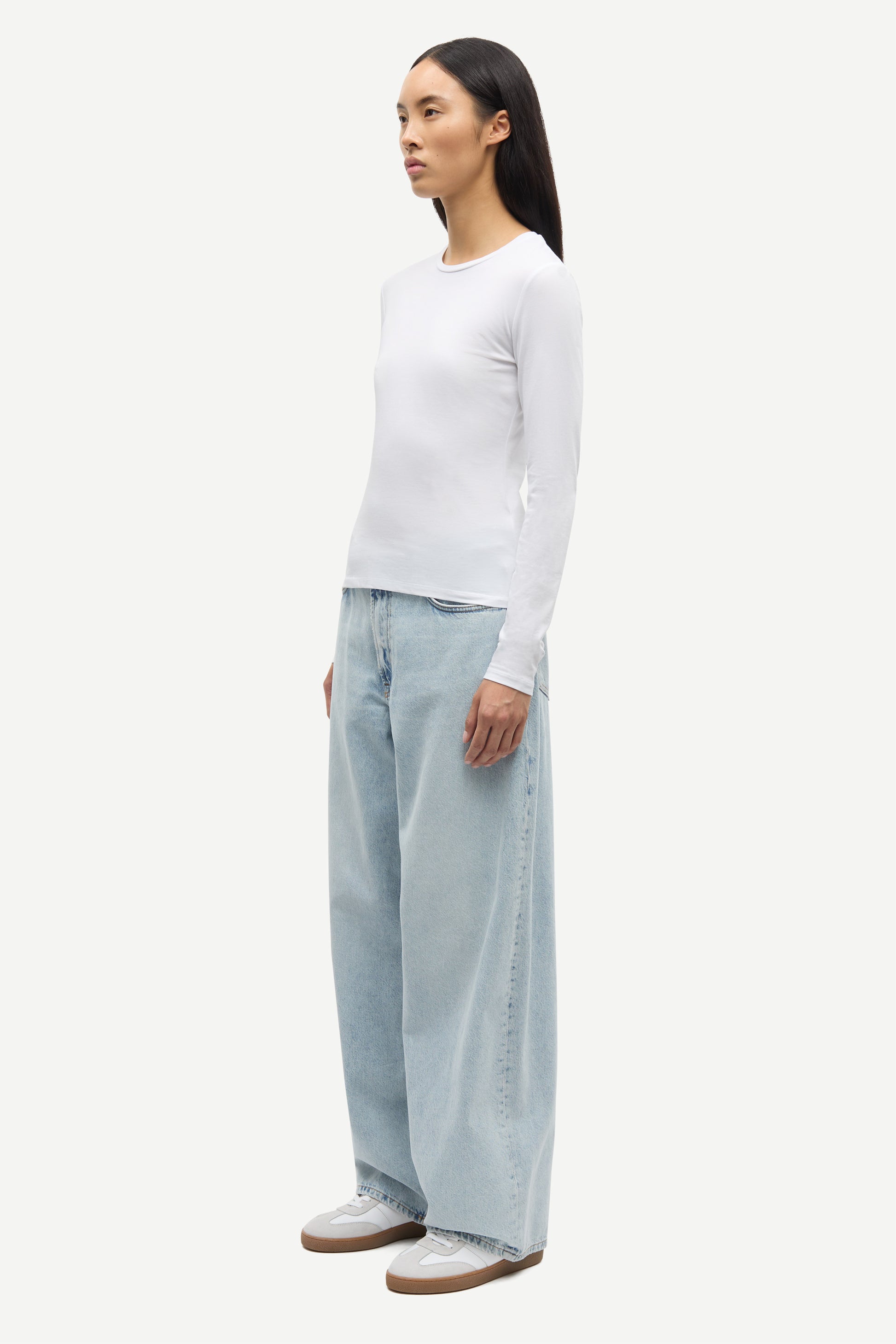 Woman wearing a white long-sleeve top and light blue pants on a white background from Samsoe Samsoe