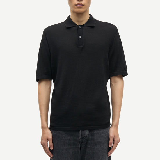 Man wearing a black polo shirt and dark jeans on a white background from Samsoe Samsoe