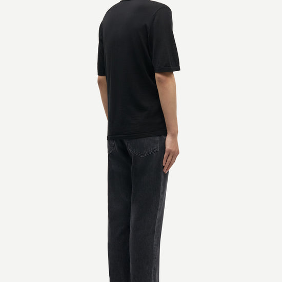 Rear view of black extra fine marino wool polo shirt worn with grey denim from Samsoe Samsoe