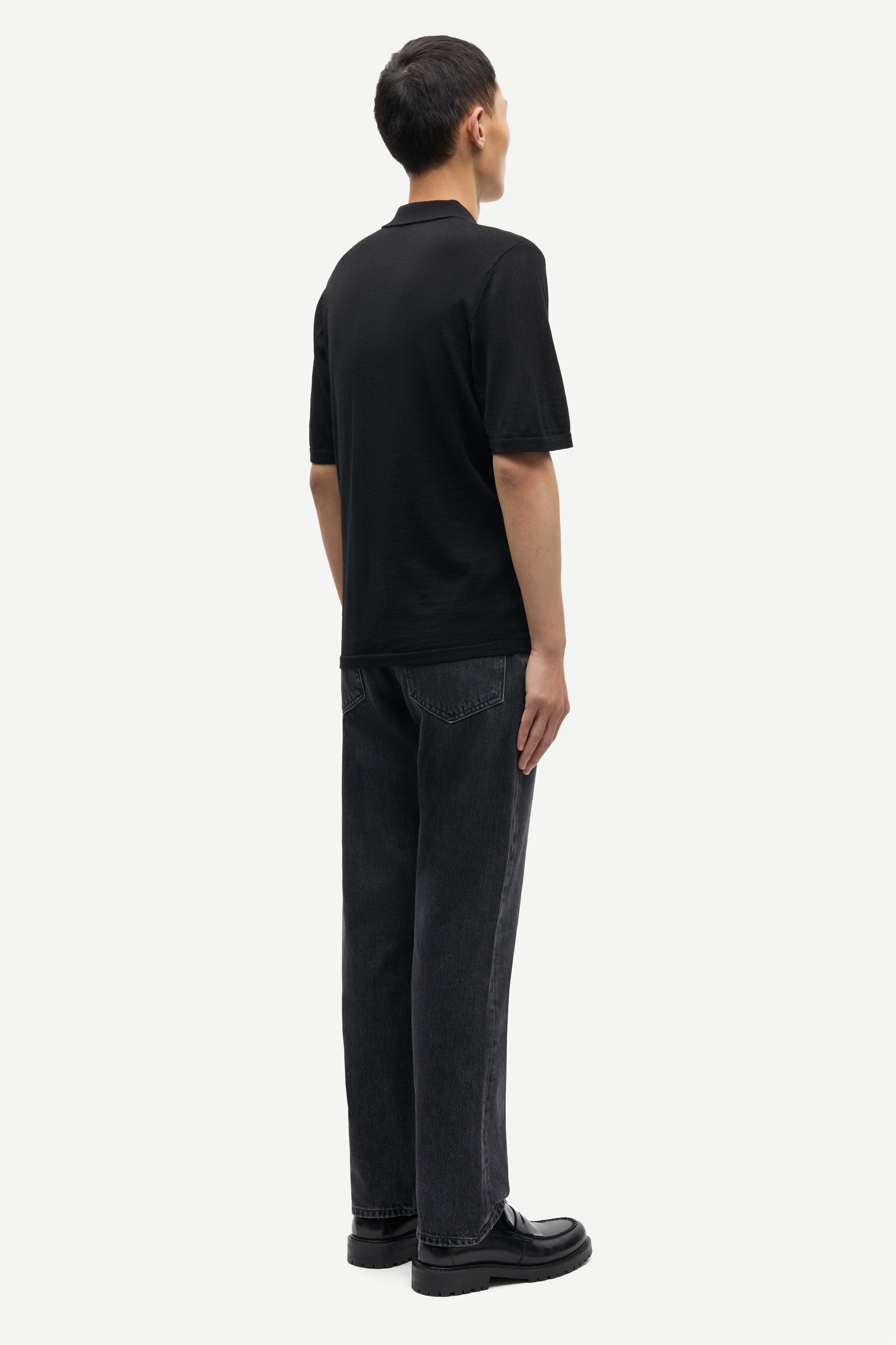 Rear view of black extra fine marino wool polo shirt worn with grey denim from Samsoe Samsoe