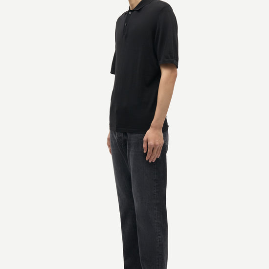 Man wearing a black polo shirt and dark jeans on a white background from Samsoe Samsoe