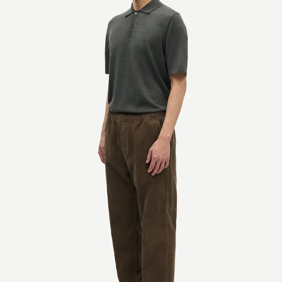 Man wearing a green polo shirt and brown pants on a white background from Samsoe Samsoe