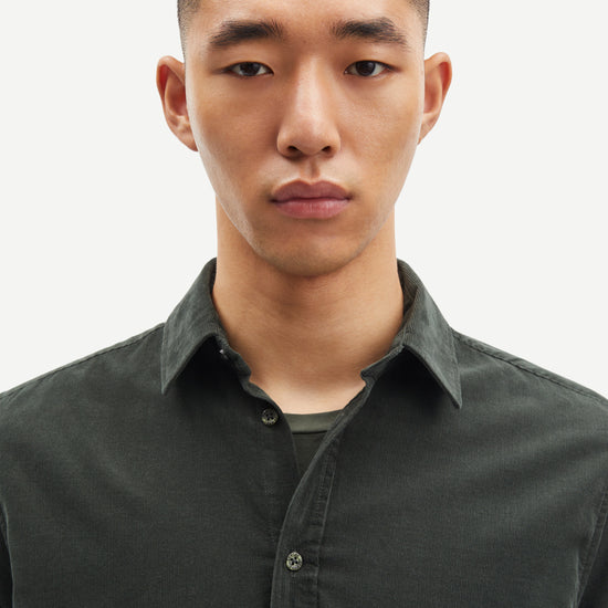 Man wearing a dark cord green shirt against a plain background