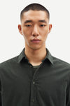 Man wearing a dark cord green shirt against a plain background