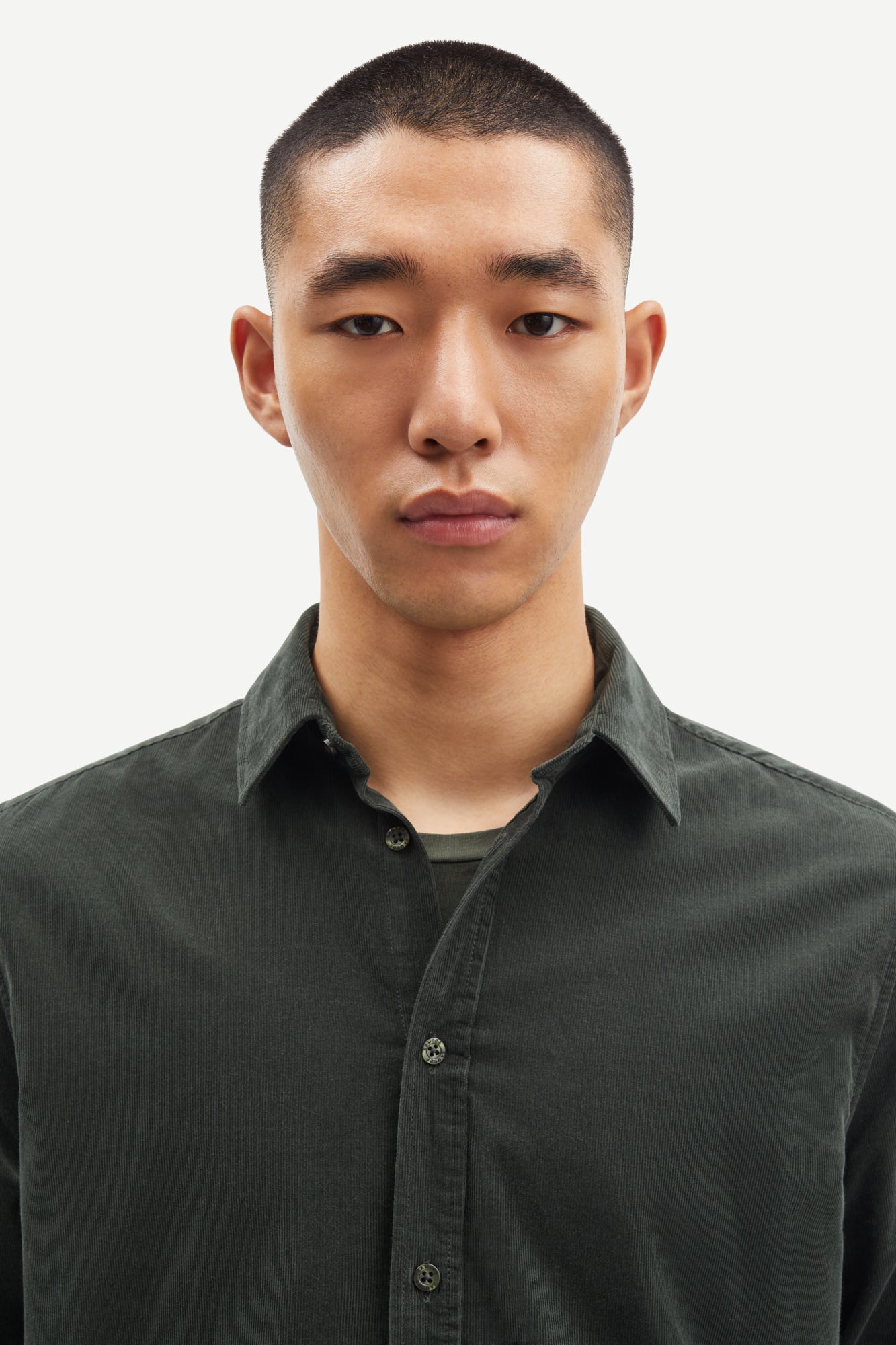 Man wearing a dark cord green shirt against a plain background